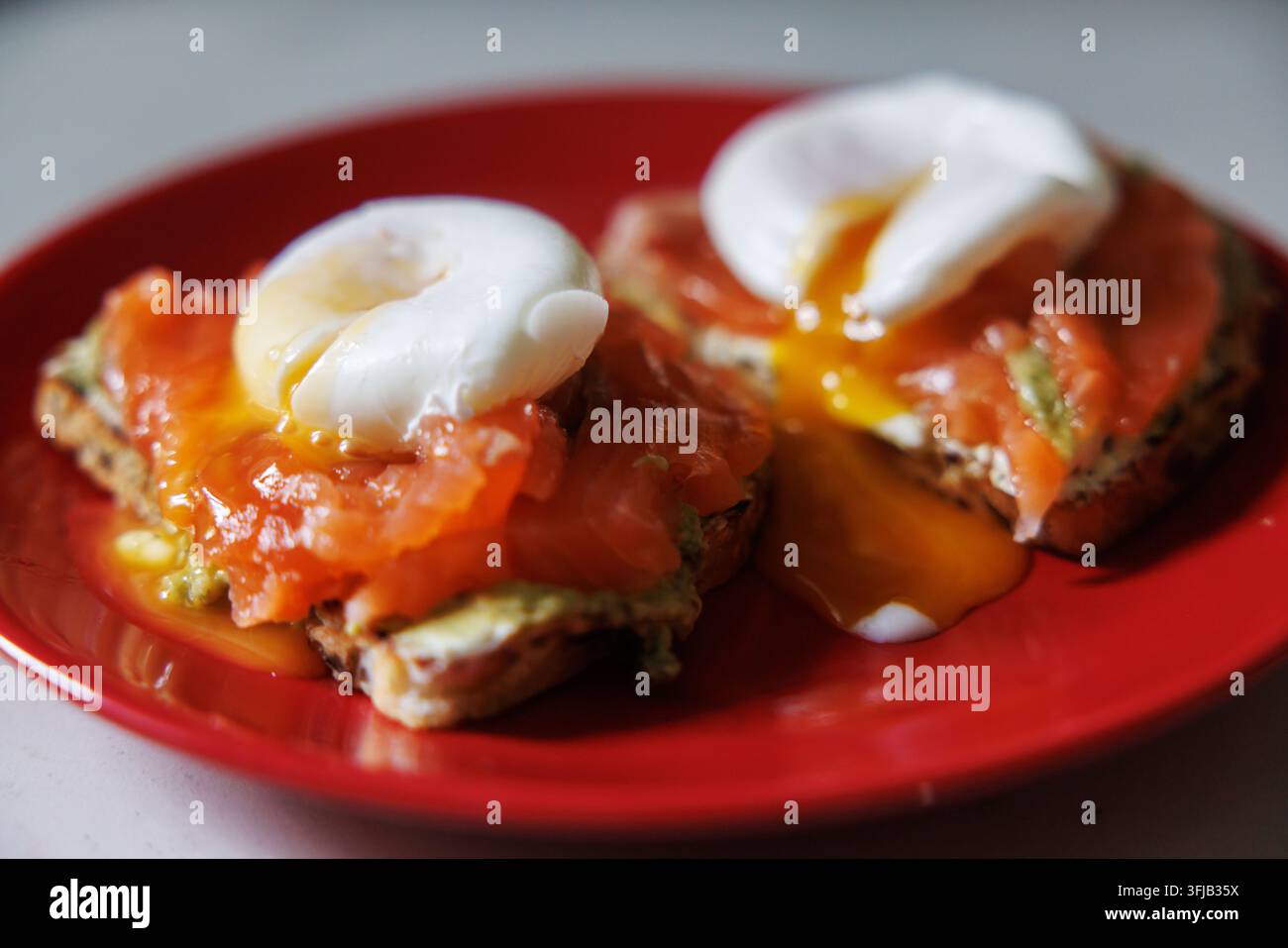 Geschmorte Eier und geräucherte Forelle auf Toast mit Avocado Stockfoto