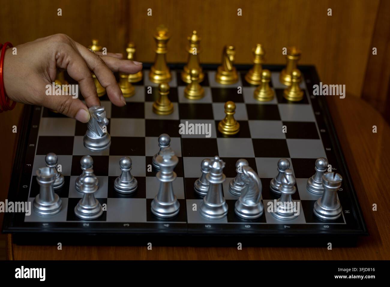 Ein konzentriertes Studiod Foto einer Frauenhand, die sorgfältig eine Schachfigur auf einem Schachbrett bewegt. Stockfoto