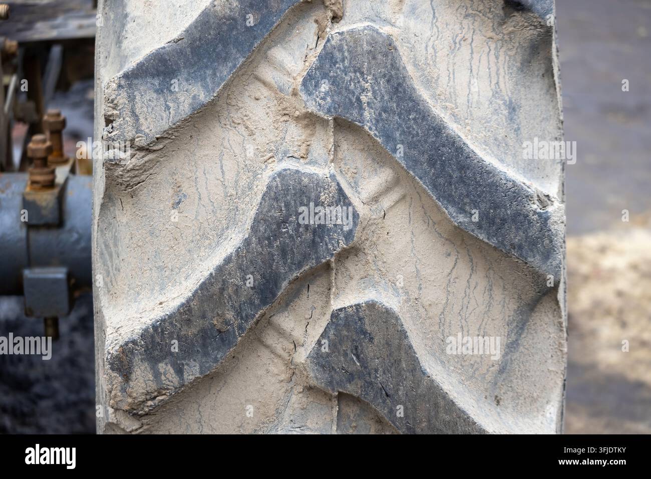 Extremer Makro-Nahaufnahme eines schmutzigen strapazierfähigen Traktorreifenprofils, bedeckt mit trockenem Schlamm und Erde. Stockfoto