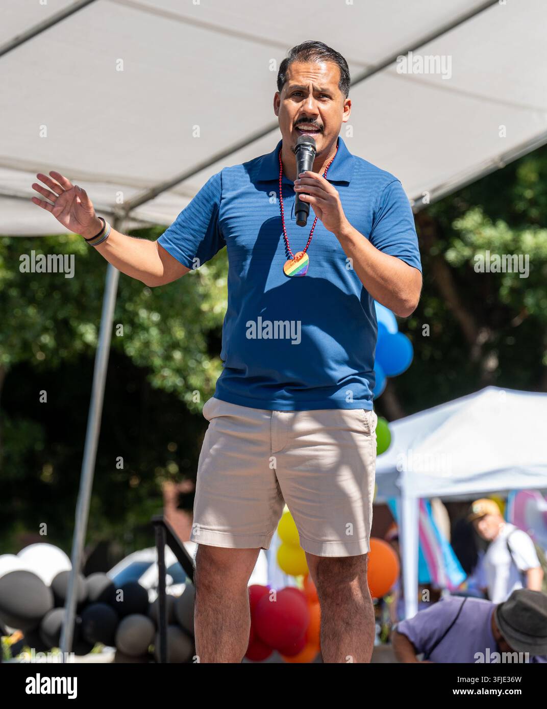 Der offen schwule Stadtratsmitglied Mario Enriquez spricht in ein Mikrofon auf der Bühne. Stockfoto
