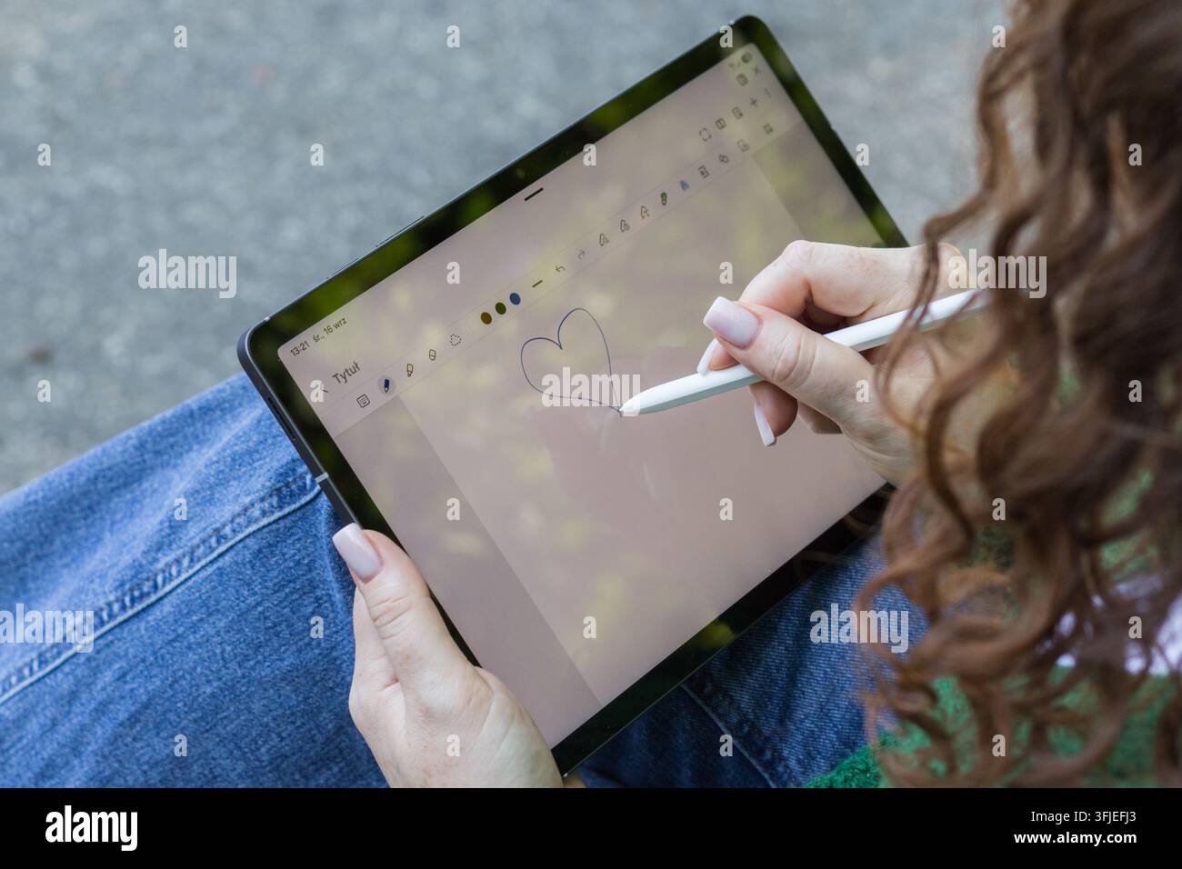 Person, die mit einem Stift auf einem Tablet-Touchscreen ein Herz zeichnet, von oben betrachtet. Stockfoto
