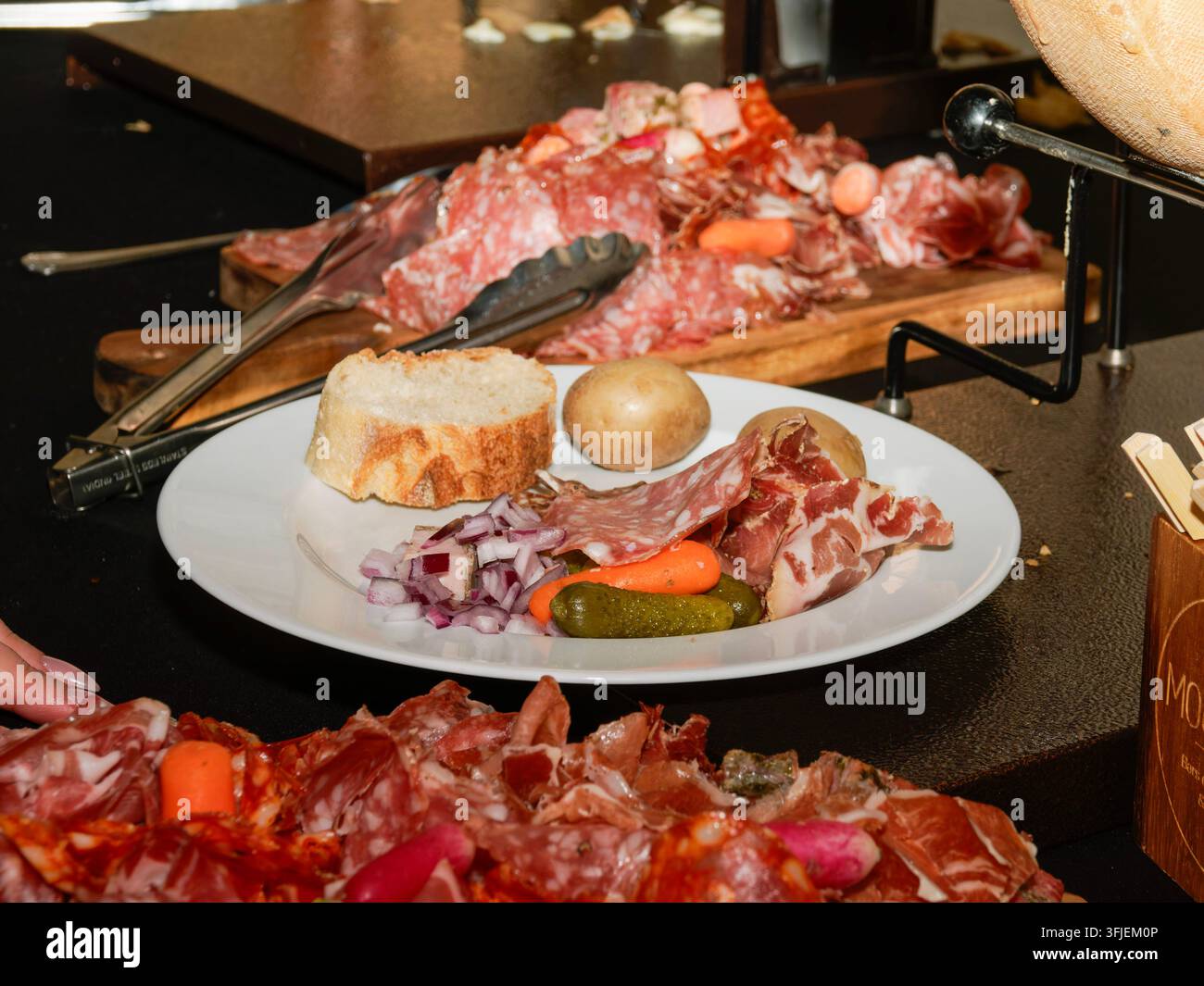 Schinkenteller mit verschiedenen Aufschnittsorten, Gurken, Zwiebeln und Brot auf einem Tisch. Stockfoto
