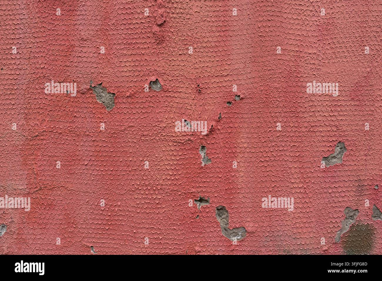 Strukturierte Wand, bedeckt mit verwittertem rotem Putz, wodurch eine gealterte architektonische Oberfläche für Grunge-, Bau- und Hintergrundkonzepte entsteht. Stockfoto