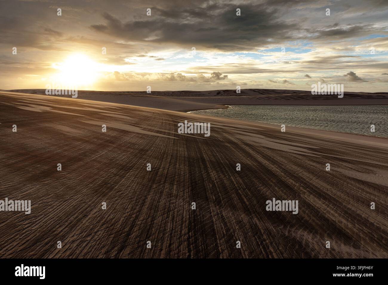 Ein spektakulärer goldener Sonnenuntergang über den Lencois Maranhenses, der weite weiße Sanddünen mit windgekräuselten Linien und makellose blaue Lagunen zeigt Stockfoto