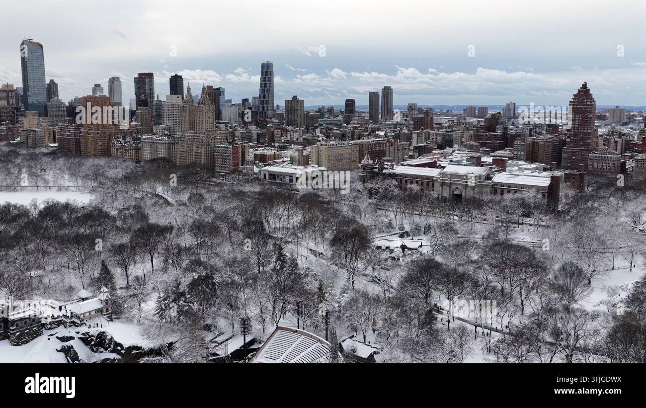 Ein atemberaubender Weitwinkel-Drohnenbild, das die schneebedeckten Bäume des Central Parks mit der ikonischen Skyline von Manhattan unter einem Winterhimmel einfängt, New York, New Stockfoto