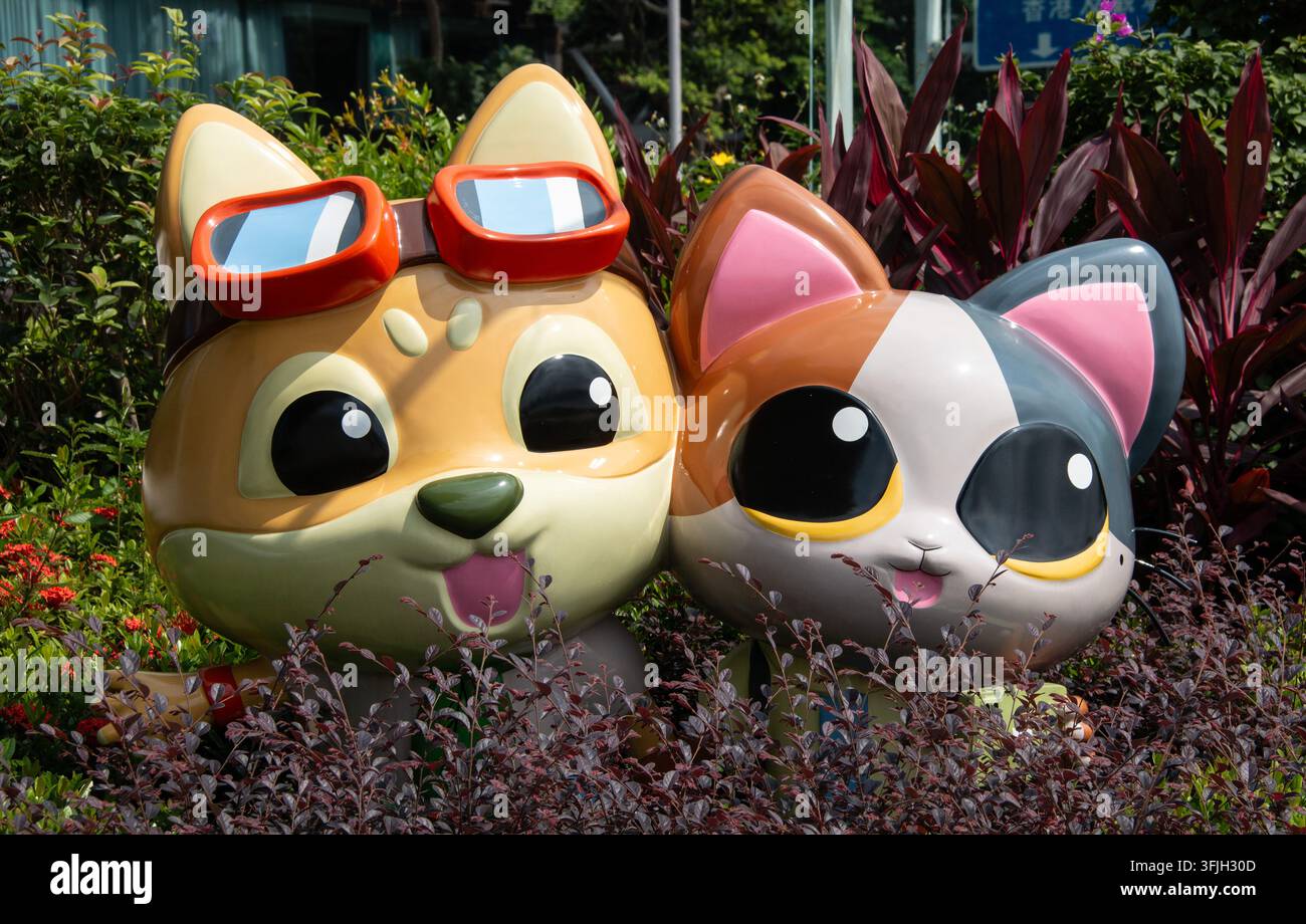 Bezaubernde farbenfrohe Cartoonskulpturen mit verspielten Ausdrücken, umgeben von üppiger Grünflora entlang der berühmten Avenue of Stars in Tsim Sha Tsui, Hongkong Stockfoto