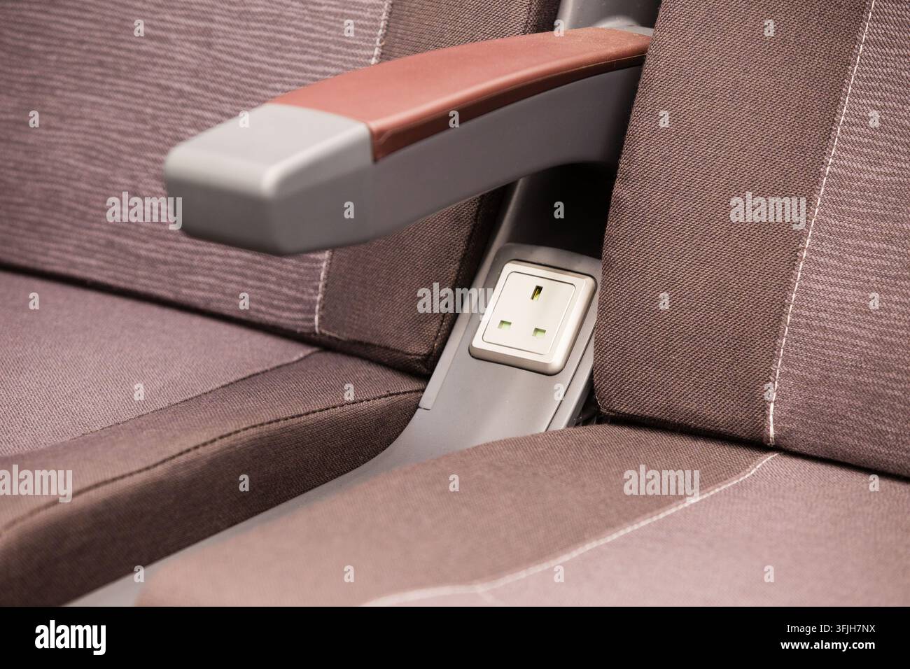 Eine britische Steckdose mit drei Stiften zwischen den Erste-Klasse-Sitzen in einem LNER-Azuma-Zug, die es den Passagieren ermöglicht, Geräte während der Zugfahrt aufzuladen. Stockfoto
