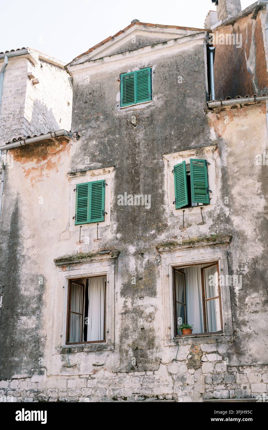 Verwittertes Steingebäude mit grünen Fensterläden Stockfoto