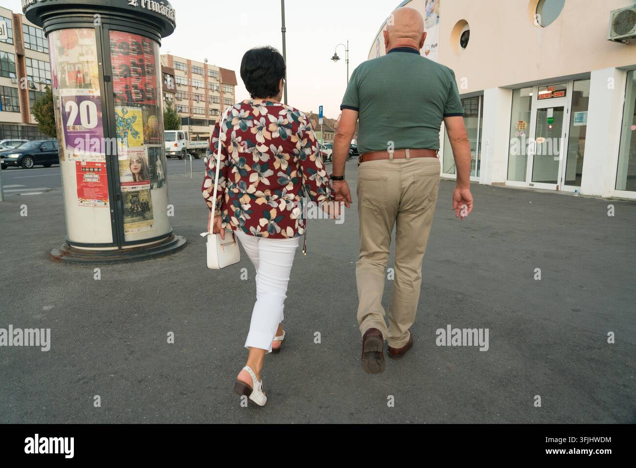 Ein älteres Paar schlendert Hand in Hand an der Markthalle Cibin in Sibiu, Rumänien, vorbei und genießt einen romantischen Nachmittagsrundgang. Stockfoto
