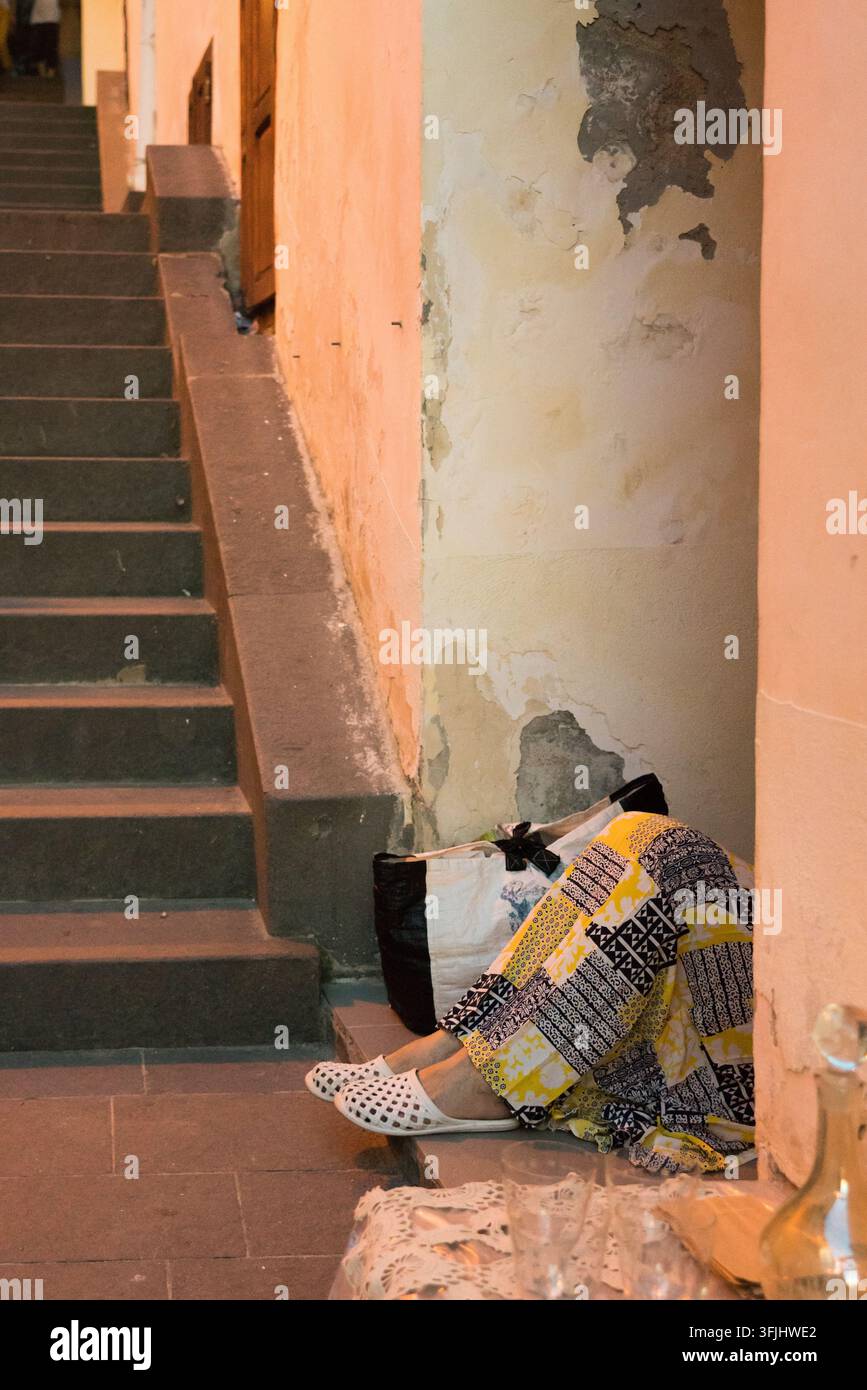 Ein Reisender ruht auf Steinstufen neben abgenutzten Stuckwänden Stockfoto