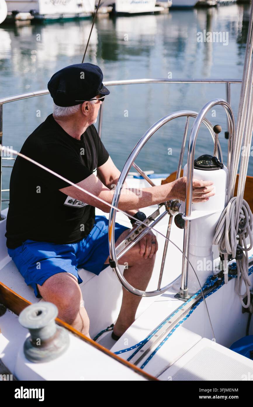 Älterer Mann am Steuer eines Segelboots Stockfoto