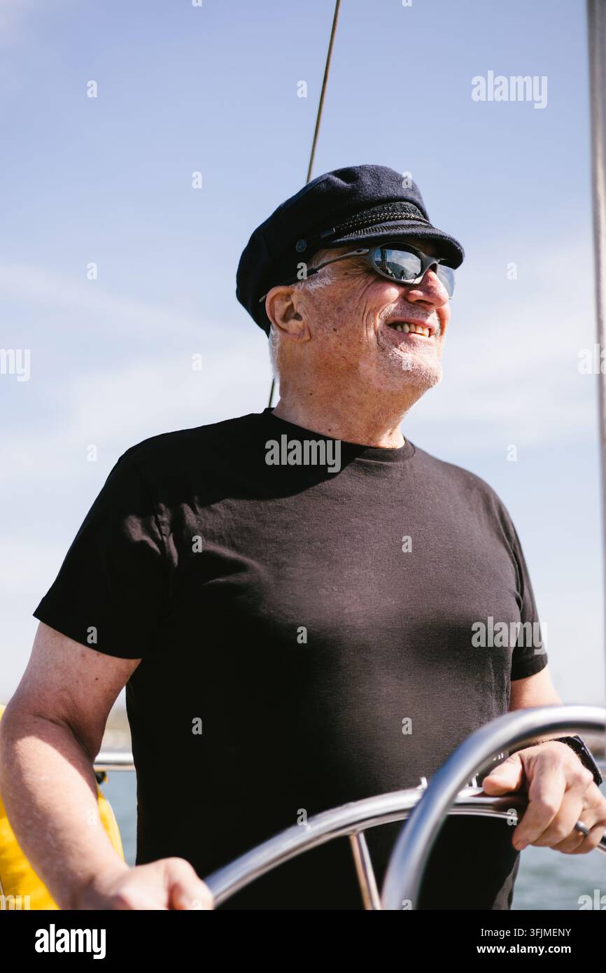 Glücklicher Senior mit einem lustigen T-Shirt segelt ein Boot Stockfoto