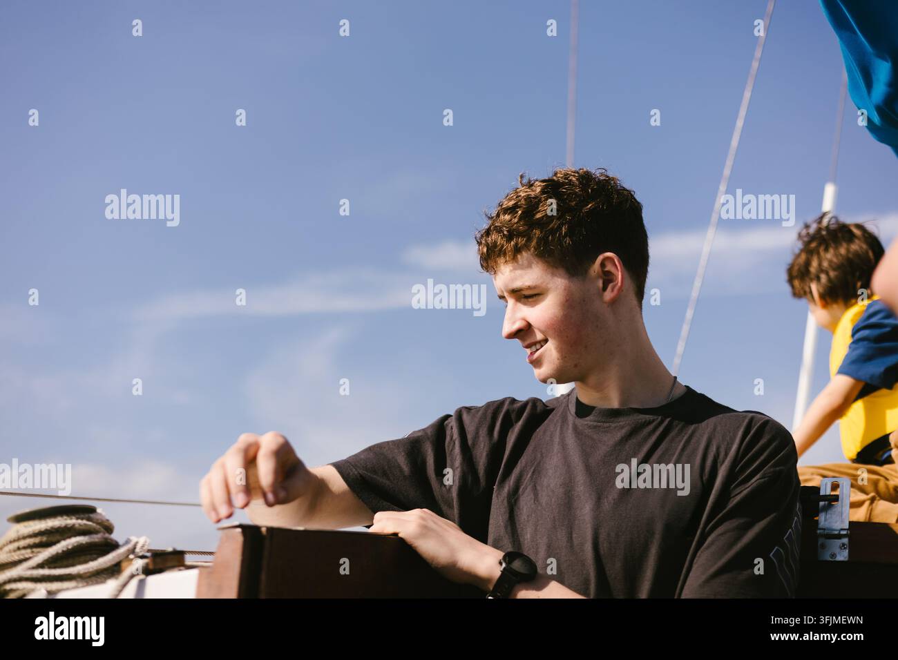 Junger Mann genießt einen sonnigen Tag auf einem Segelboot Stockfoto