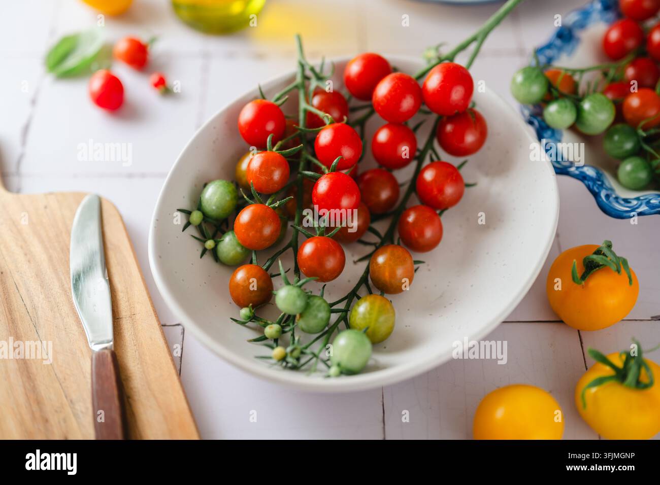 Bunte Kirschtomaten auf einer hellen weißen Küchentheke Stockfoto