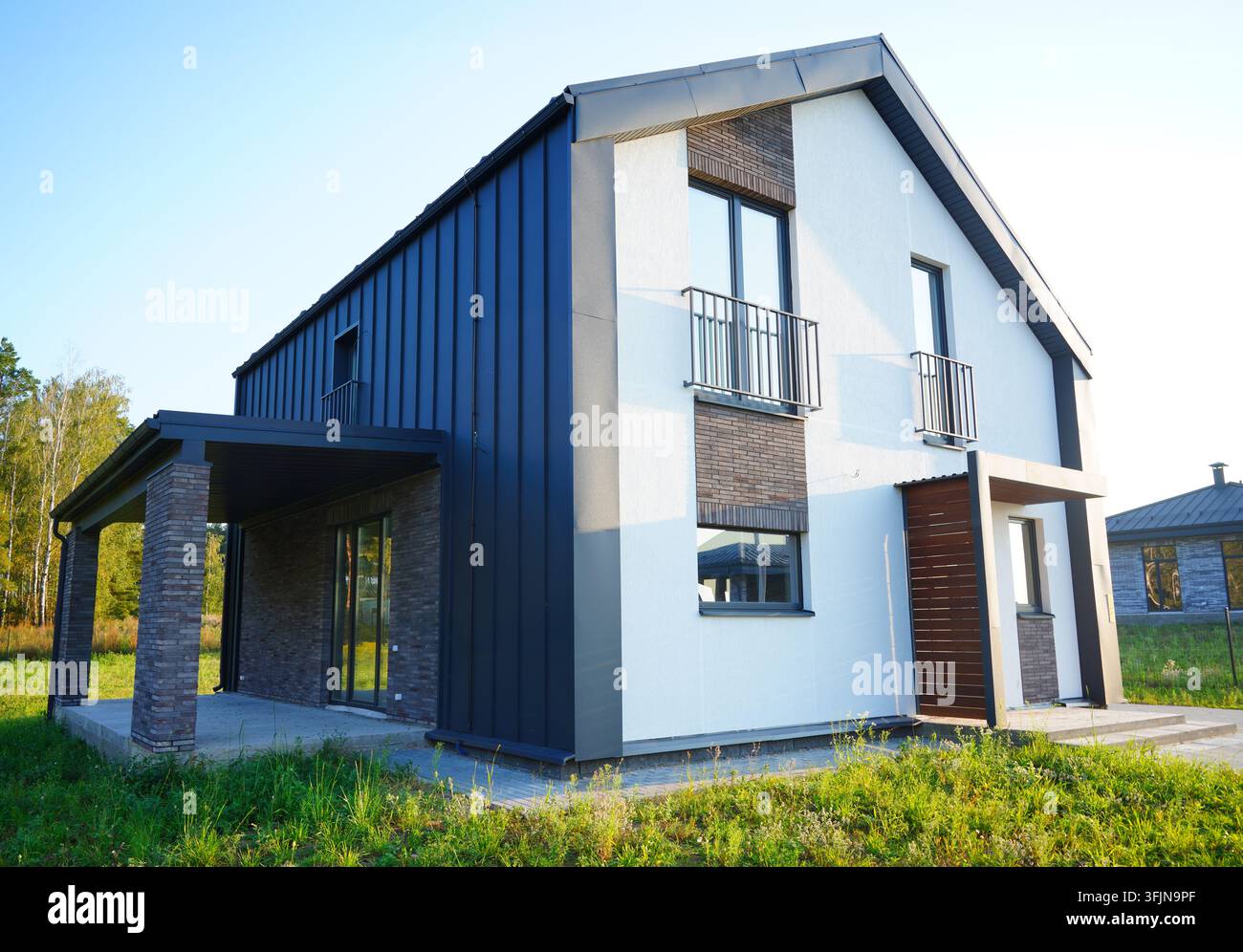 Modernes Vorstadthaus. Barnhouse zeichnet sich durch geometrische Scheunenform, ein Giebeldach ohne Überstände und einen rechteckigen Grundriss aus. Die Fassade kombiniert vertikale Stockfoto