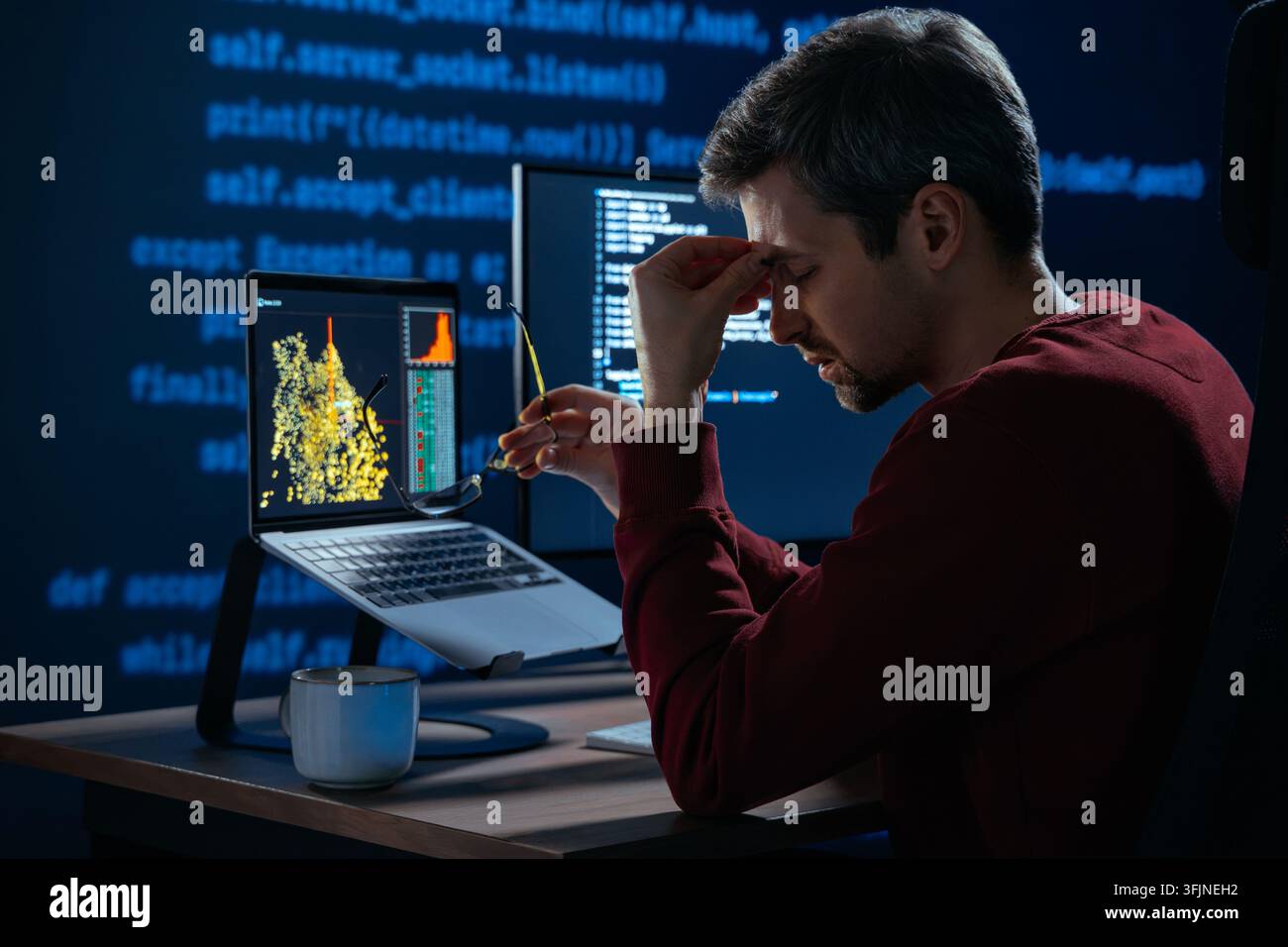 Ermüdeter Entwickler entfernt die Brille und reibt sich die schmerzenden Augen während intensiver Nachtprogrammierarbeit, die durch blaues Licht und längere Bildschirmzeit verursacht wird. Überarbeiteter Coder steht vor Burnout am Computertisch Stockfoto
