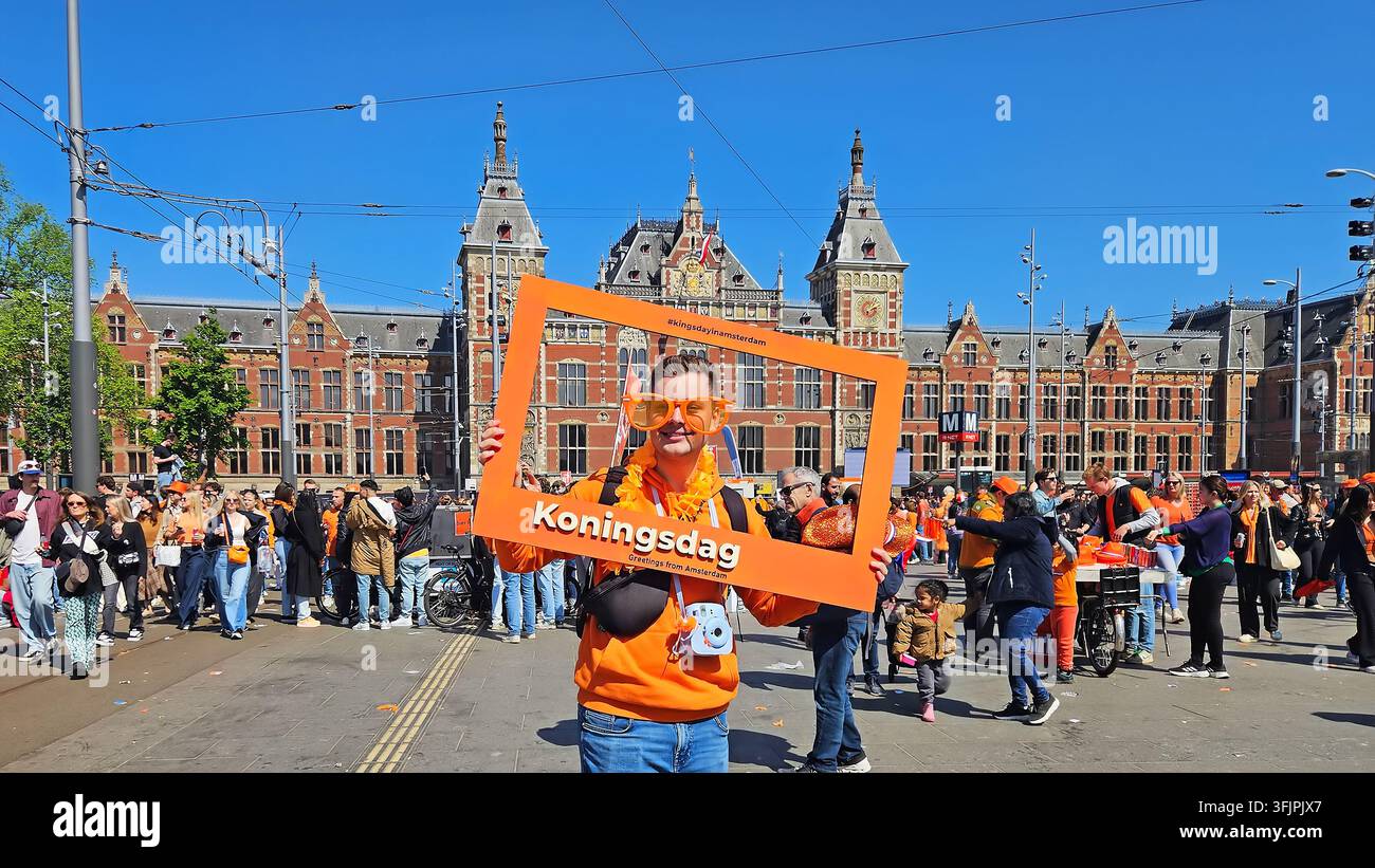 AMSTERDAM, NIEDERLANDE - 27. April 2026: Niederländischer Mann in orangefarbener Kleidung am Amsterdamer Hauptbahnhof während des Königstages Stockfoto
