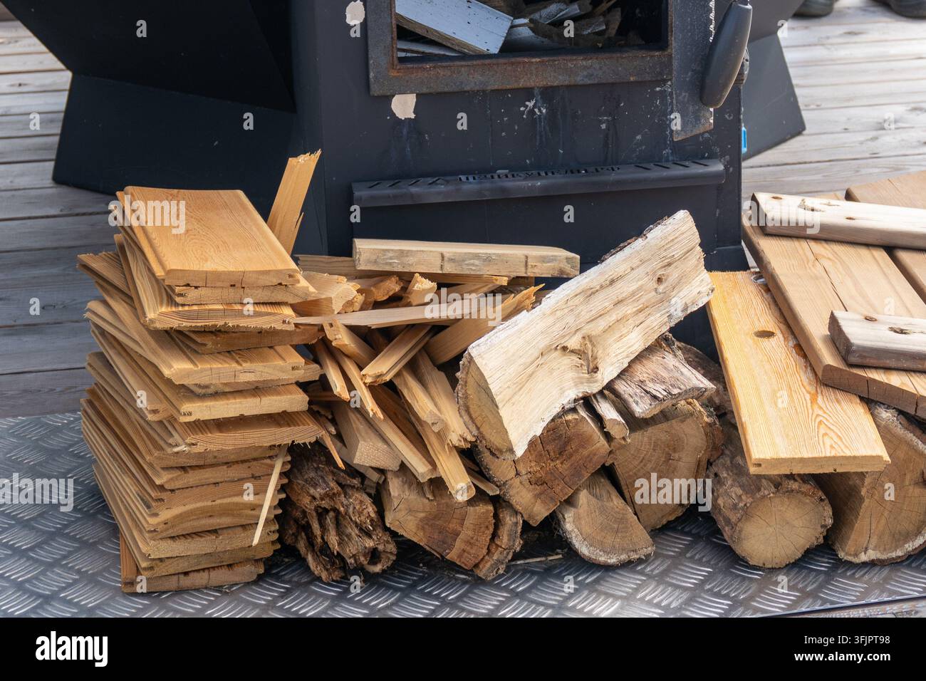 Stapel Feuerholz und Holzbretter in der Nähe eines Außenofens Stockfoto