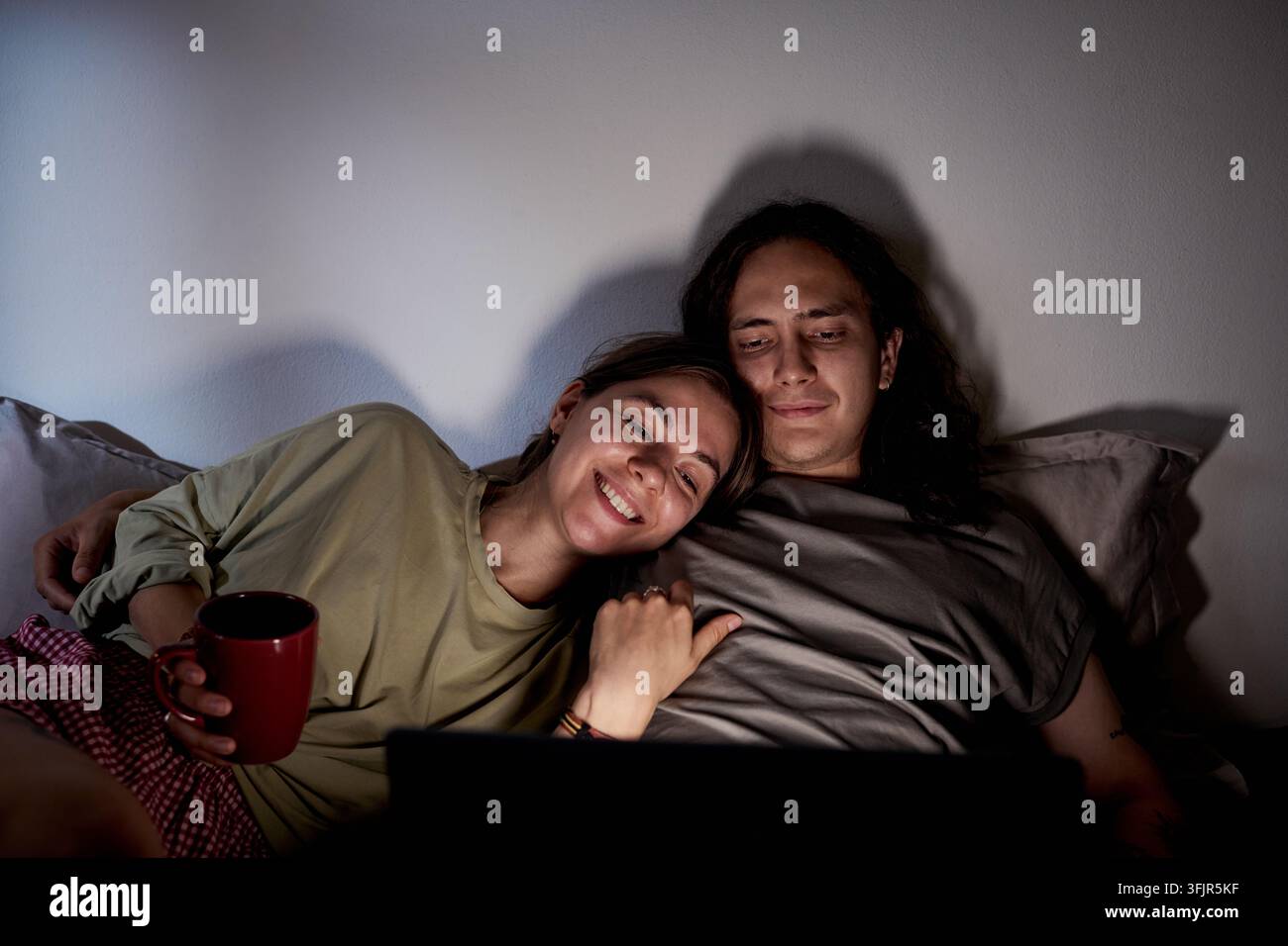 Paar schaut Film auf dem Laptop im Bett am Abend zu Hause Stockfoto