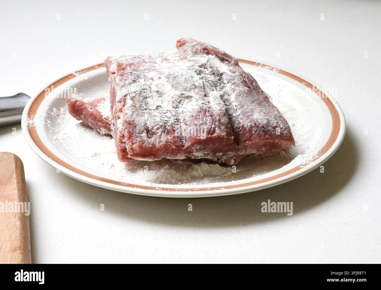 Frisches Rindfleisch auf einem Teller auf einem rustikalen Holztisch serviert, zeigt rohes Fleisch, Lebensmittelzubereitung, Kochzutaten und traditionelles Küchenkonzept Stockfoto