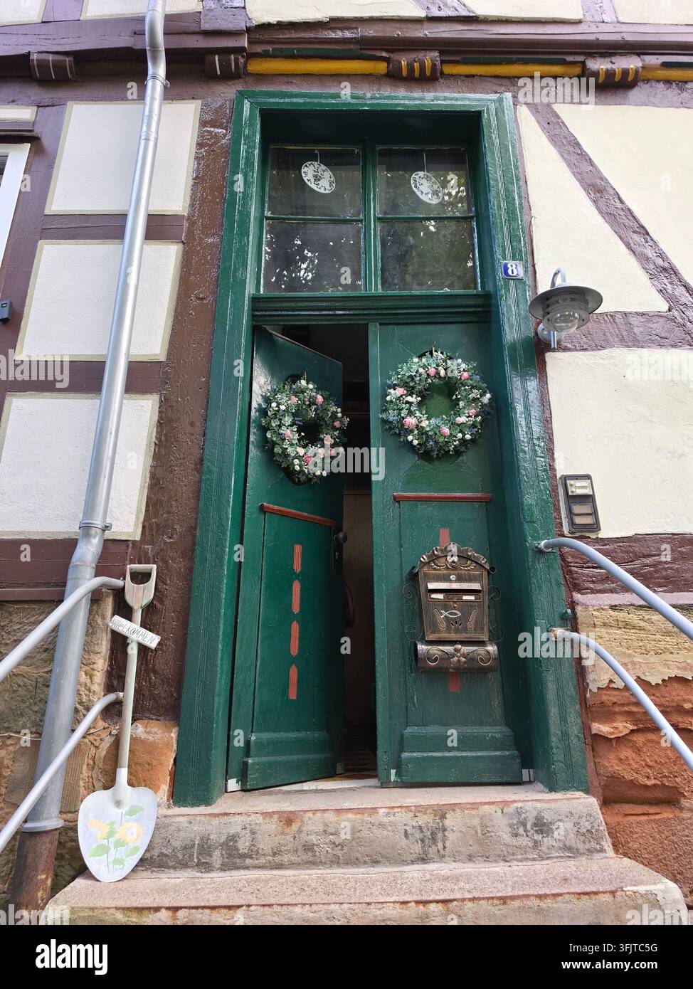 Bezaubernde vintage grüne Holztür mit Weihnachtskränzen und Dekorationen an einem traditionellen Fachwerkhaus. Alter rustikaler Eingang mit Briefkasten, Stein Stockfoto