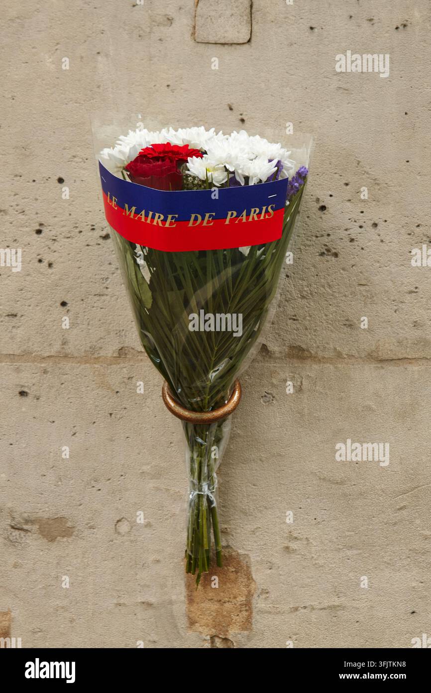 Paris, Frankreich – 08. Mai 2026: Strauß aus roten Rosen und weißen Chrysanthemen, eingewickelt in ein blaues und rotes Band des Bürgermeisters von Paris, ausgestellt vor einem Wetter Stockfoto