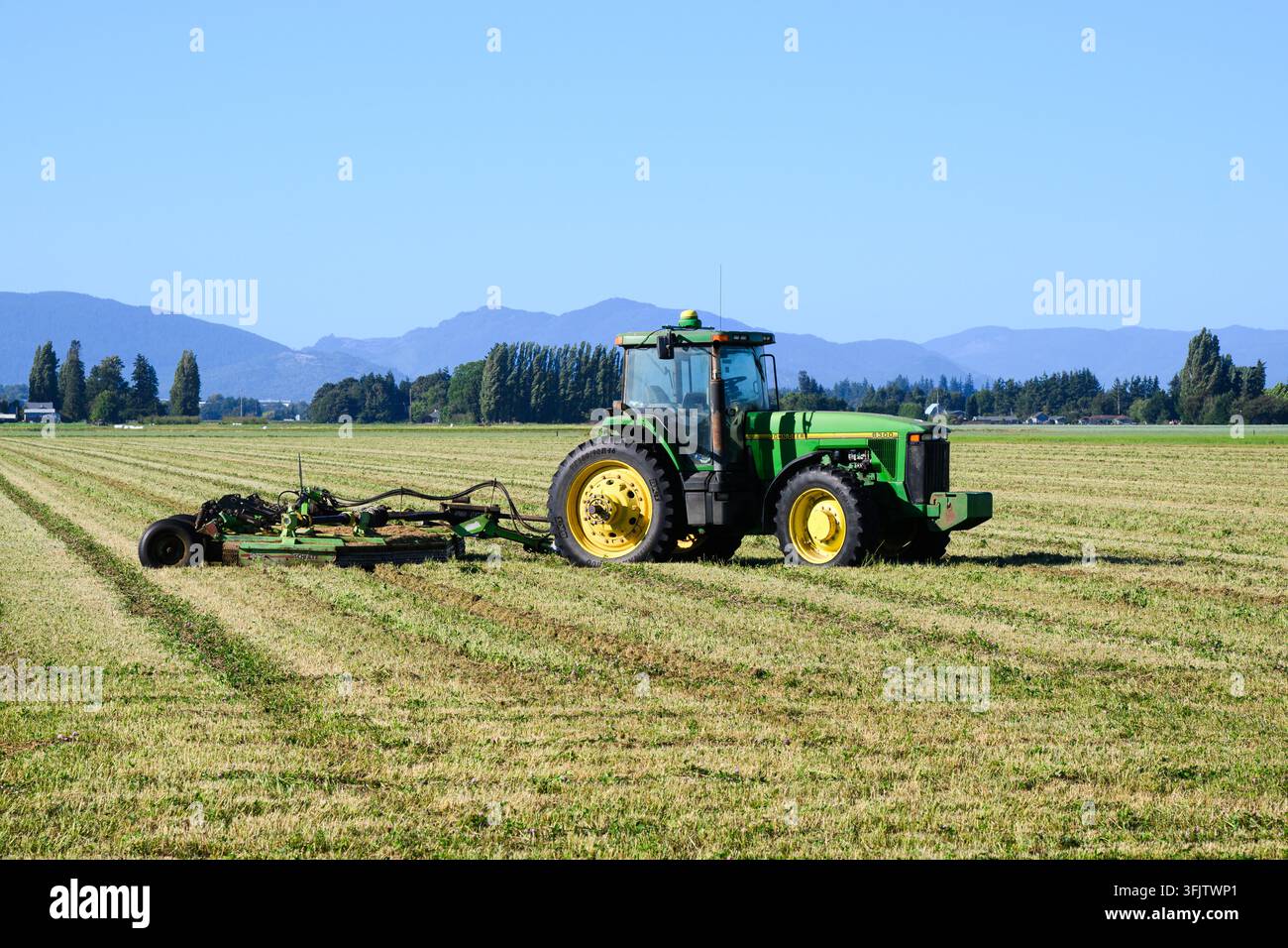 Mount Vernon, WA, USA - 8. August 2026; John Deere 8300 Zehrenfrüchte-Traktor mit 5026 Schulte-Rotorschneider in gemähtem Feld Stockfoto