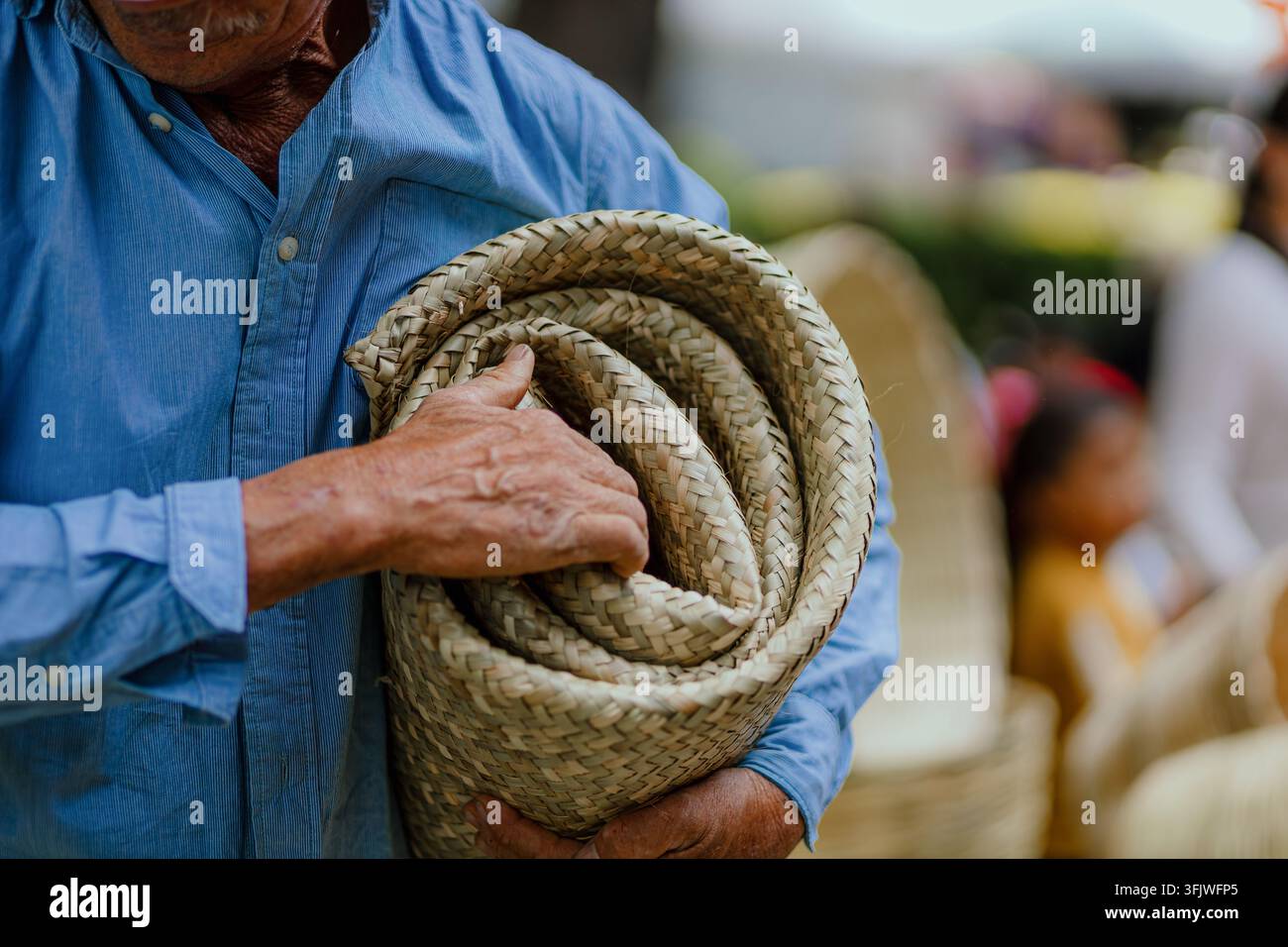 San Pedro Cholula, Mexiko - 8. September 2026: Ein Mann hält eine gerollte gewebte Matte auf dem traditionellen Tauschmarkt in Puebla. Stockfoto