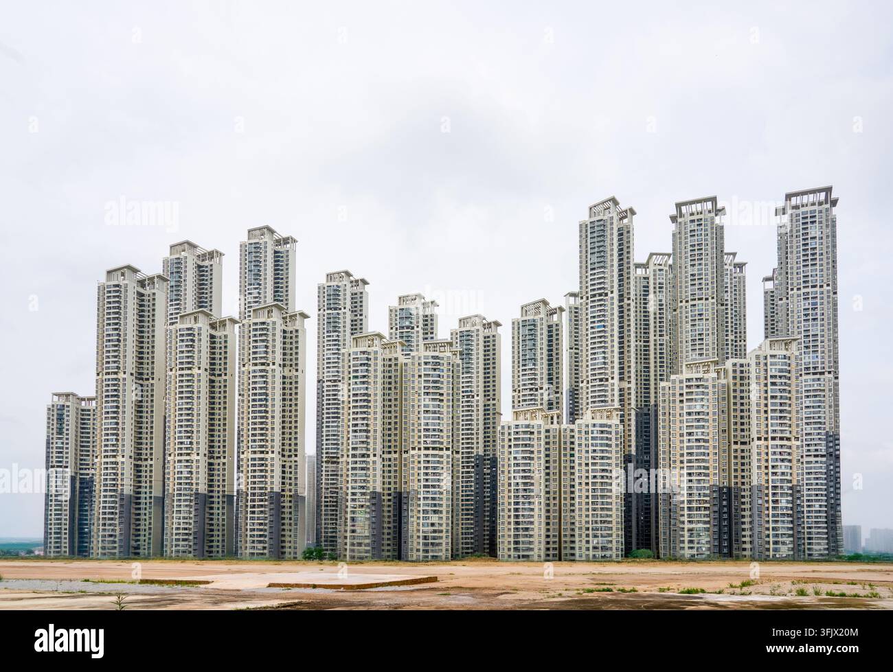 Panoramische Ansicht der städtischen Hochhaus-Wohnbauten von Nanning. Cremefarbene Türme sind dicht in eine Skyline angeordnet, mit unentwickeltem roten Boden Stockfoto