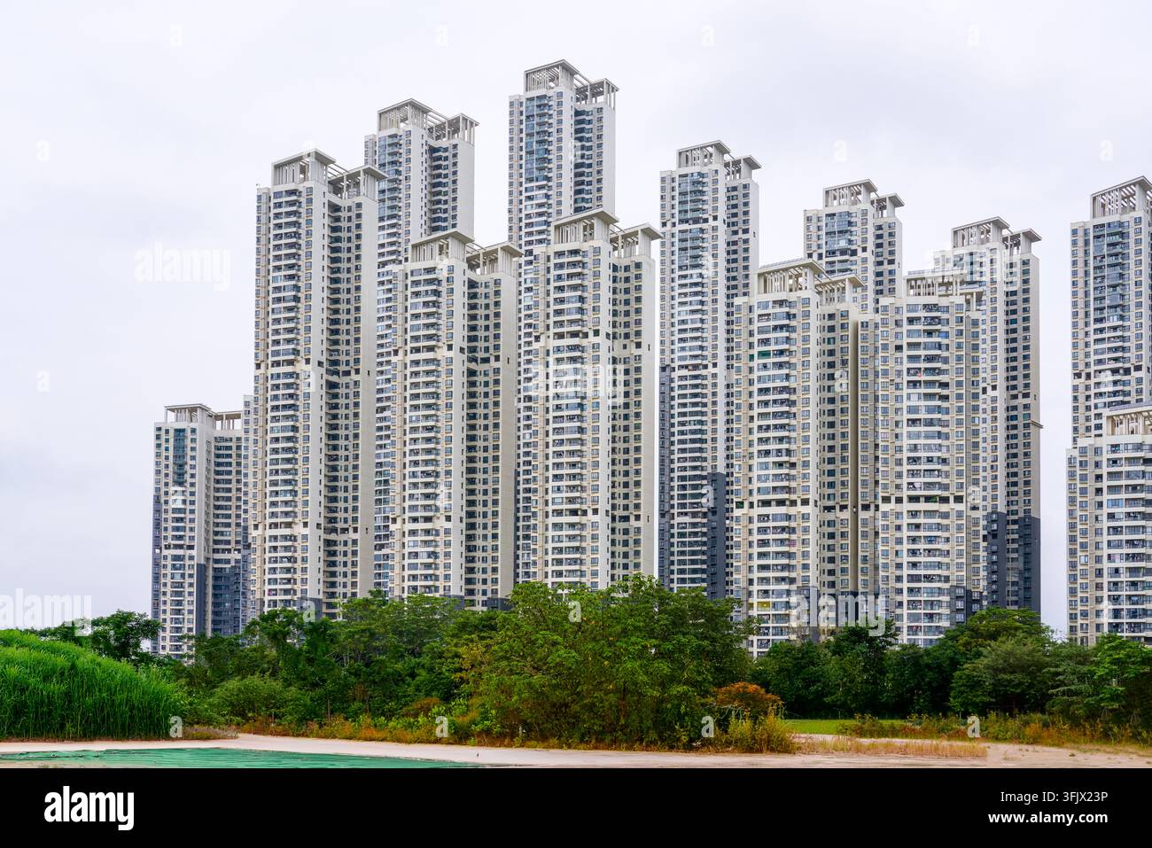 Städtische Hochhaus-Wohngebäude von Nanning und Grünflächen im Vordergrund, dichte moderne Türme sind unter einem bewölkten Himmel angeordnet, die das Land zeigen Stockfoto