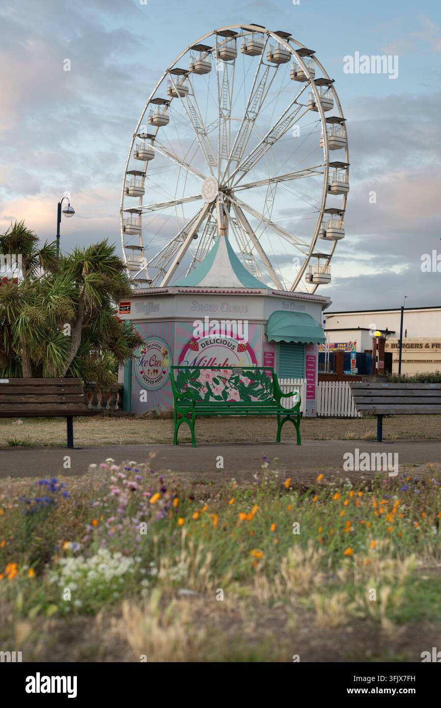 Im Barry Island Pleasure Park in Wales genießen Besucher klassische Strandfahrten und süße Leckereien in der Nähe des ikonischen Riesenrads und des Lebensmittelkiosks. Stockfoto