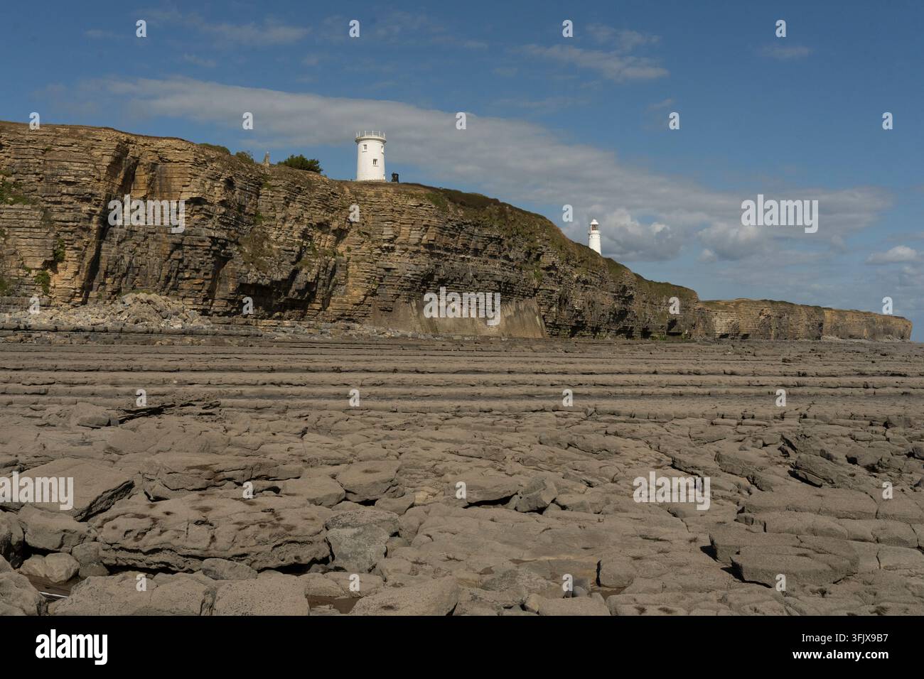 Niedrigwasser an Nash Point, Wales, zeigt felsige Strände und geschichtete Klippen, wo zwei Leuchttürme stehen, um Schiffe zu führen und Schiffbrüche zu verhindern. Stockfoto