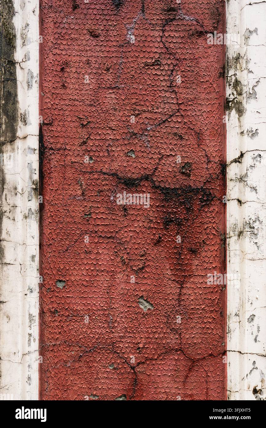 Nahaufnahme einer rauen roten texturierten Oberfläche mit sichtbarer Reliefstruktur und Gebrauchsspuren. Die Oberfläche ähnelt bemaltem Material oder einer gealterten Beschichtung. Stockfoto