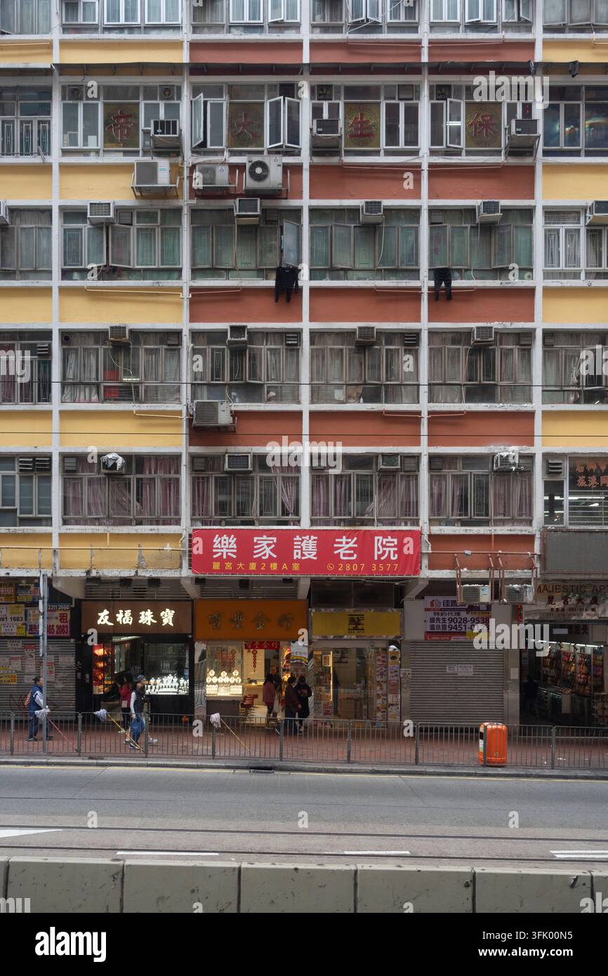 Fußgänger gehen an Geschäften unter den Majestic Apartments (309 King's Rd, North Point, HK) vorbei, um Geschäfte in einer dichten städtischen Umgebung zu besuchen. Stockfoto