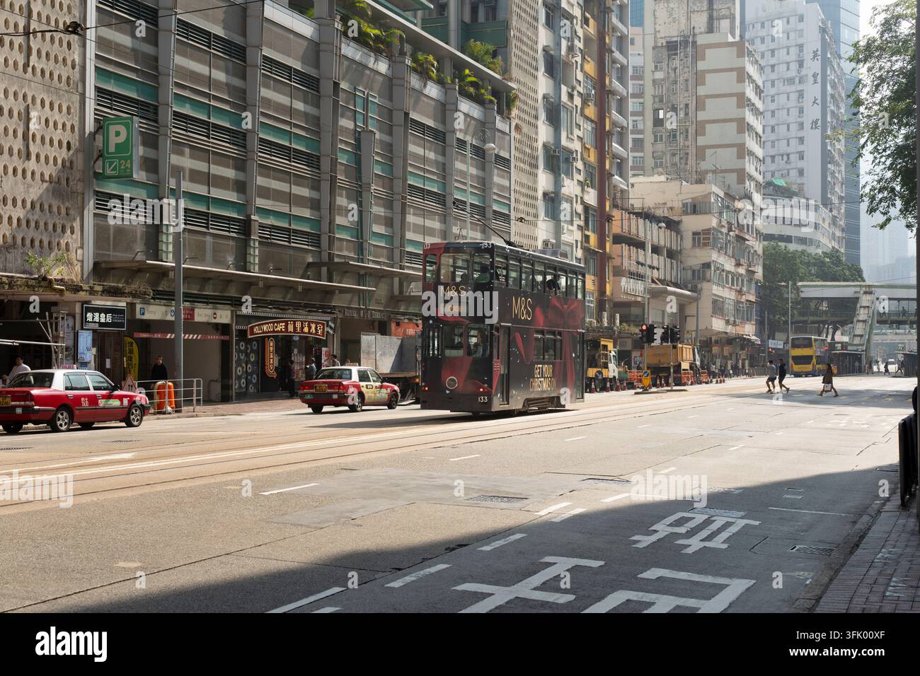 King's Road, North Point, Hongkong: Taxis, Fußgänger und eine Straßenbahn teilen sich die belebte Straße für den täglichen Verkehr. Stockfoto