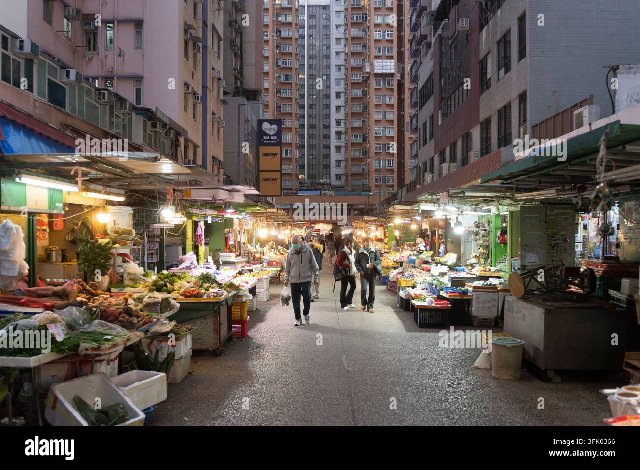 Einkäufer durchstöbern die Stände des Feuchtmarkts in North Point, Hongkong, um frische Lebensmittel unter hoch aufragenden Wohnhochhäusern zu kaufen. Stockfoto