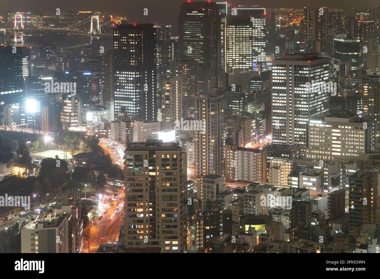Tokio bei Nacht: Beleuchtete Minato-Hochhäuser leuchten, während der Verkehr fließt, und die ikonische Regenbogenbrücke spannt sich über die Tokyo-Bucht. Stockfoto