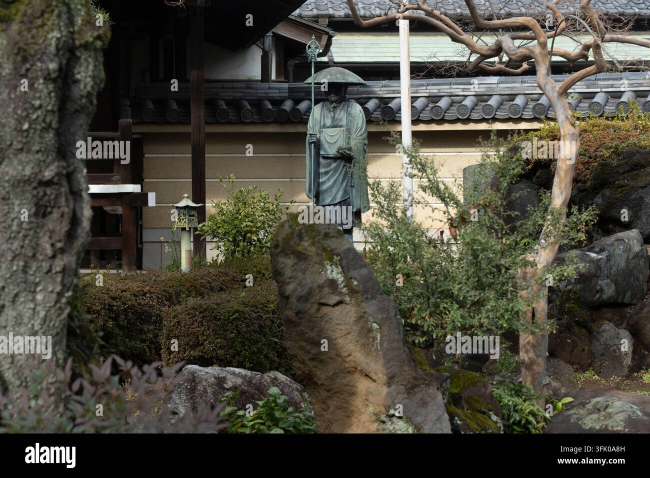 Als Ehrung des buddhistischen Erbes steht eine Mönchsstatue in dem ruhigen Garten des Shōgonji-Tempels in Japan, um spirituelle Reflexion zu inspirieren. Stockfoto