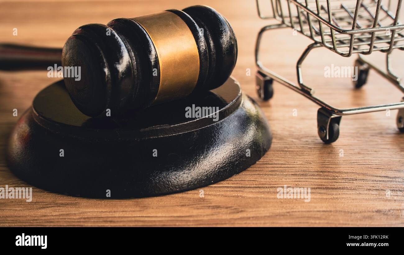 Holzener Richterhammer und Klangblock neben Miniatur-Einkaufswagen auf Holzoberfläche – Konzept für Verbraucherrechte, Einzelhandelsvorschriften und kommerzielles Recht Stockfoto