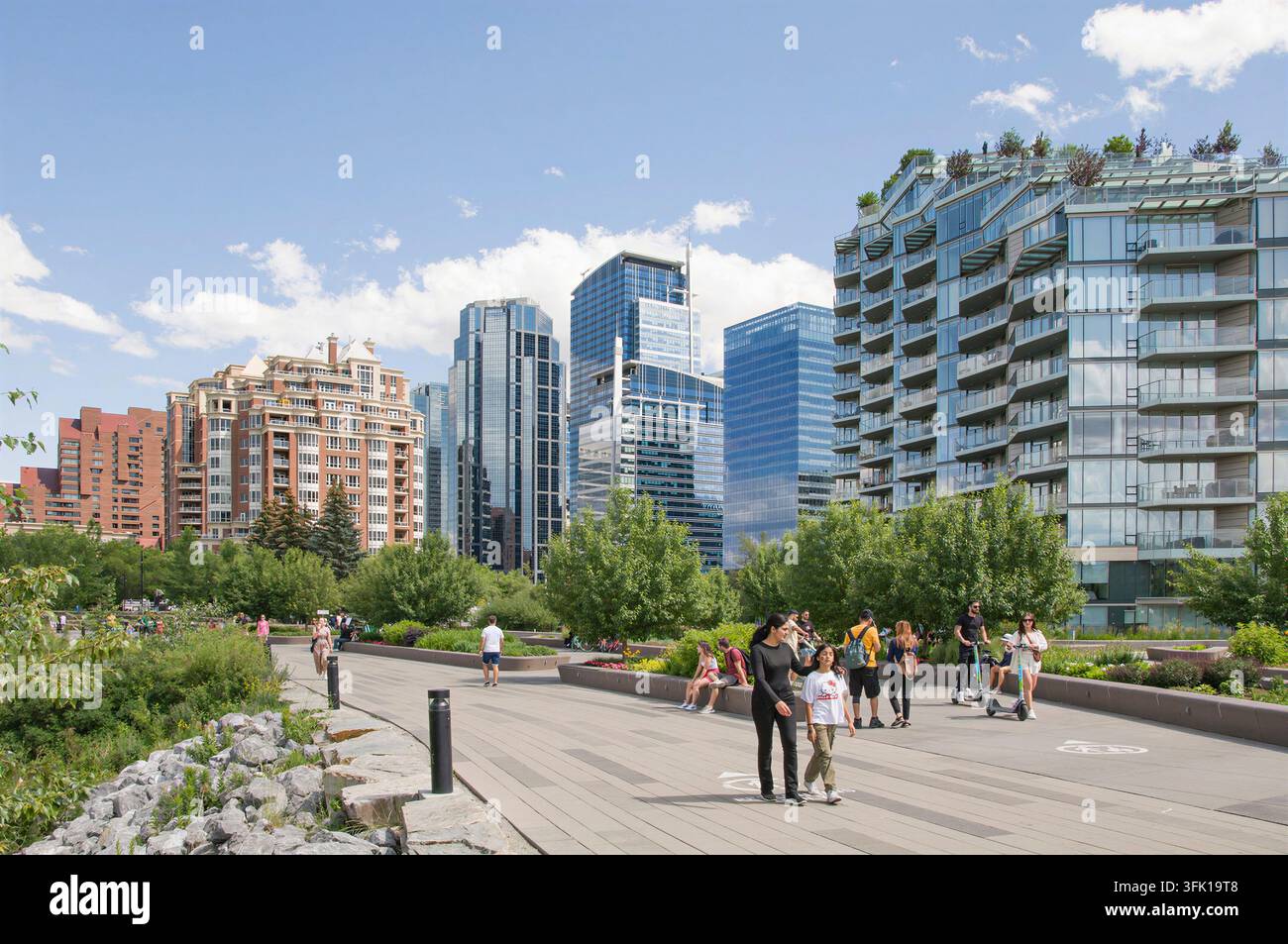 CALGARY, KANADA - 03. JULI 2023: Eine lebendige urbane Sommerszene auf der Eau Claire Promenade entlang des Bow River Pfadsystems in der Innenstadt von Calgary. Moder Stockfoto