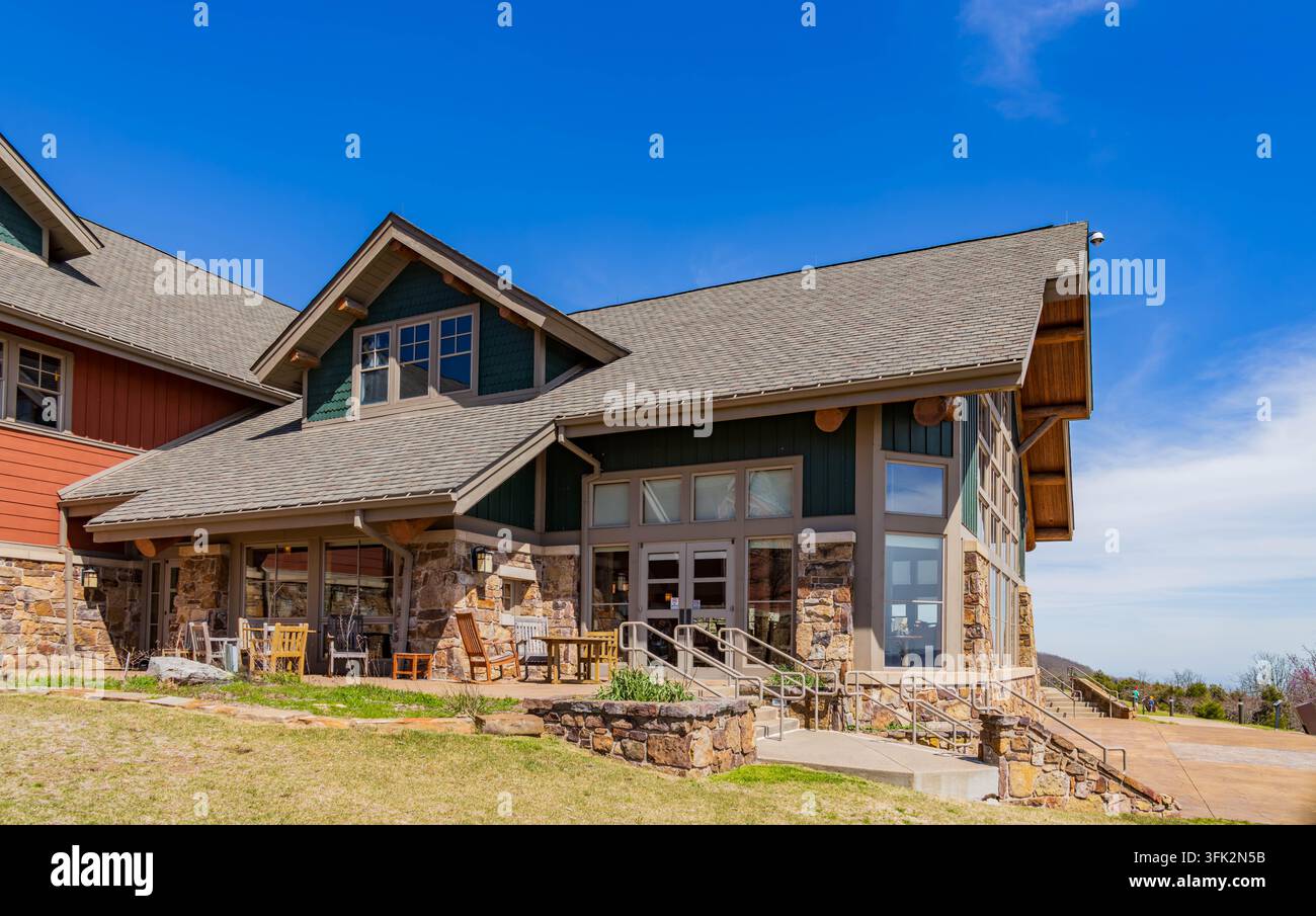 Eine rustikale Holz Lodge mit Steinakzenten verfügt über eine Terrasse mit Gartenmöbeln unter einem weiten, strahlend blauen Himmel. Stockfoto