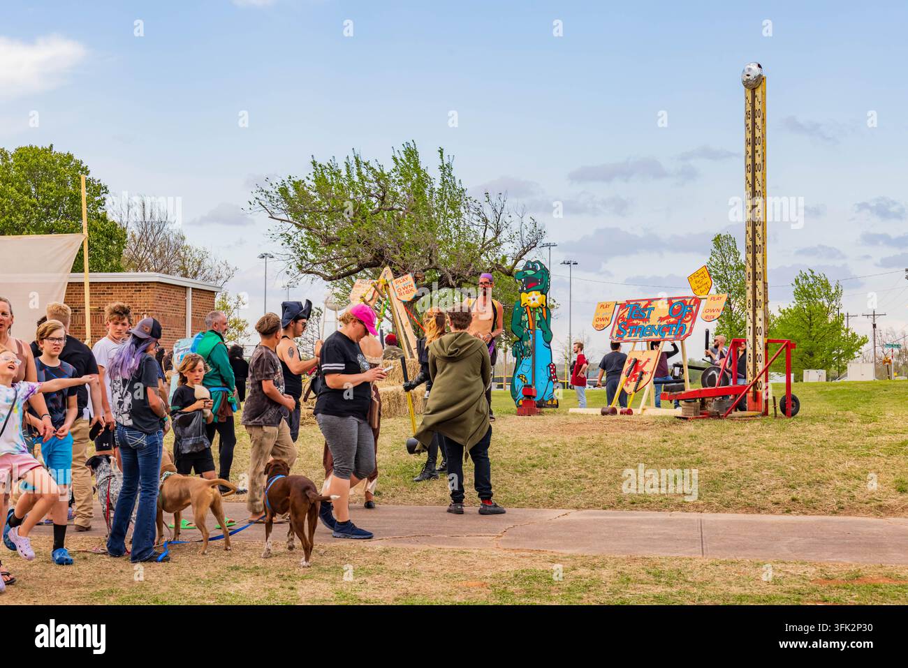 Oklahoma, Vereinigte Staaten, 06. APR 2024 – Menschen verschiedenen Alters gehen einen Weg entlang, nahe bunten Dekorationen und festlichen Ausstellungen in einer lebhaften Gemeinde Stockfoto
