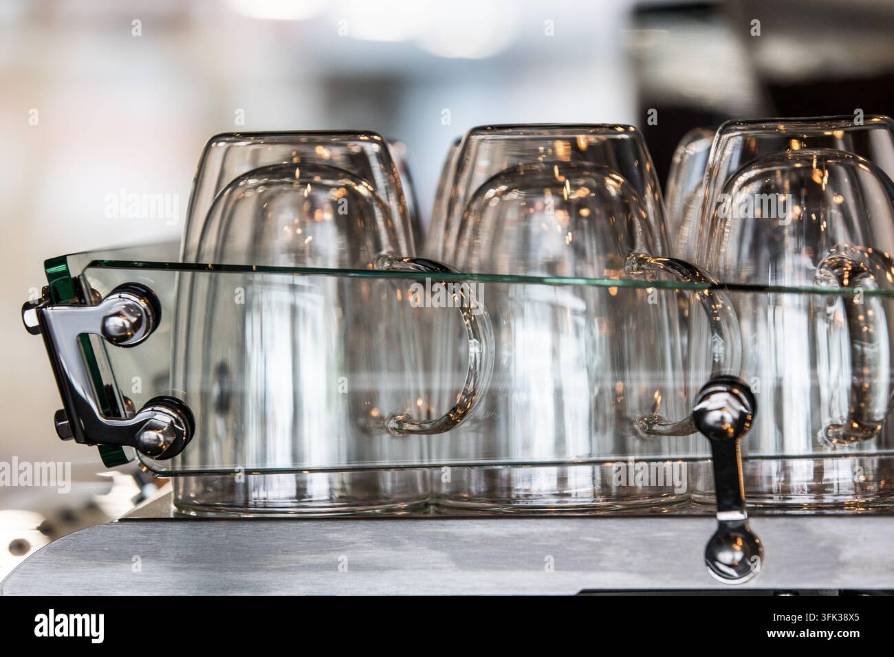 Doppelwandige Glas-Kaffeebecher stehen auf einem Espresso-Maschinen-Wärmer in einem Spezialcafé, um sie für das optimale Brühen vorzuwärmen. Stockfoto