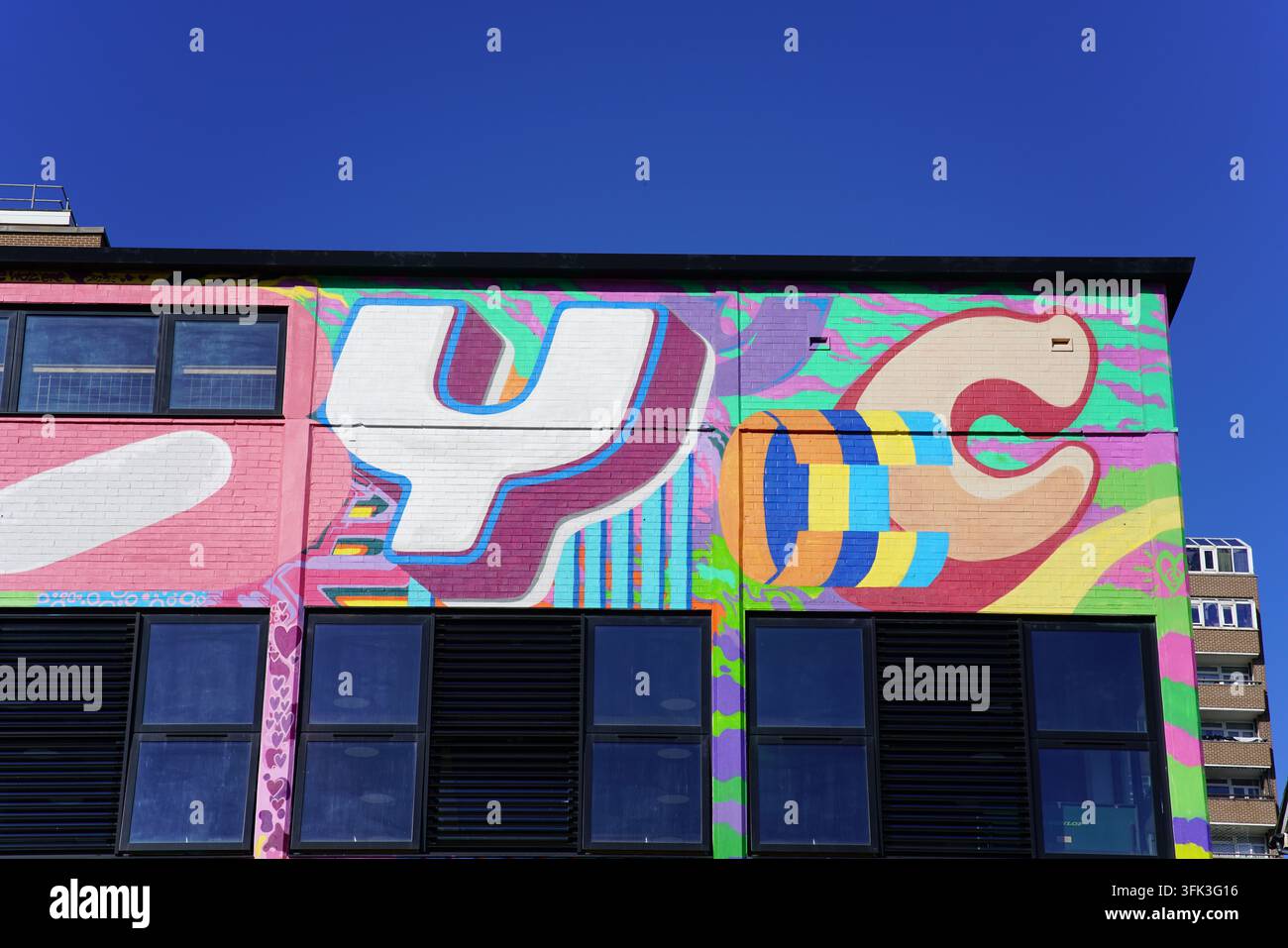 Helle Straßenmalerei, die über eine Gebäudefassade unter einem tiefblauen Himmel in Brighton, England, gemalt ist. Stockfoto