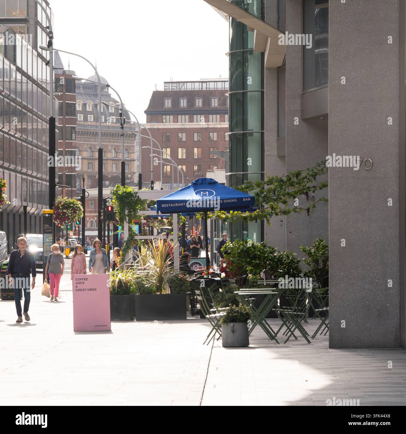 Fußgänger gehen am M Restaurant und Joe & The Juice in der 70 Victoria Street, London, vorbei und genießen die lebendige Atmosphäre des Nova-Komplexes. Stockfoto
