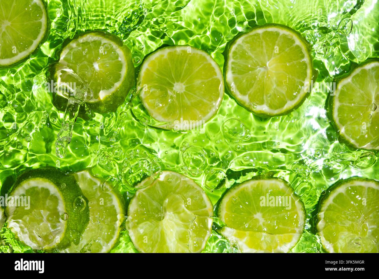 Überkopf-Aufnahme von saftigen Limettenstücken in hellem Wasser mit Wellen. Stockfoto