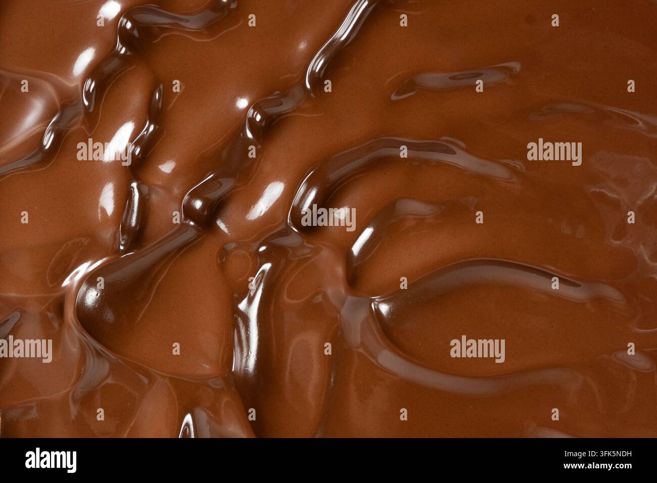 Wirbelnde flüssige Milchschokoladenstruktur mit seidenglatten Wellen. Stockfoto
