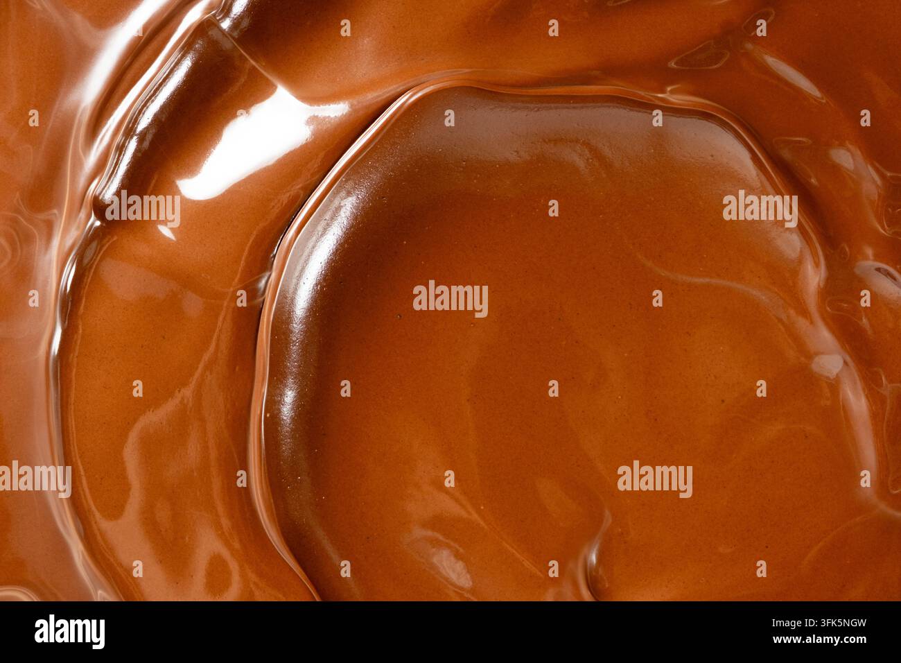 Glänzende geschmolzene Schokoladenwellen abstrakter Hintergrund vertikale Makroaufnahme. Stockfoto