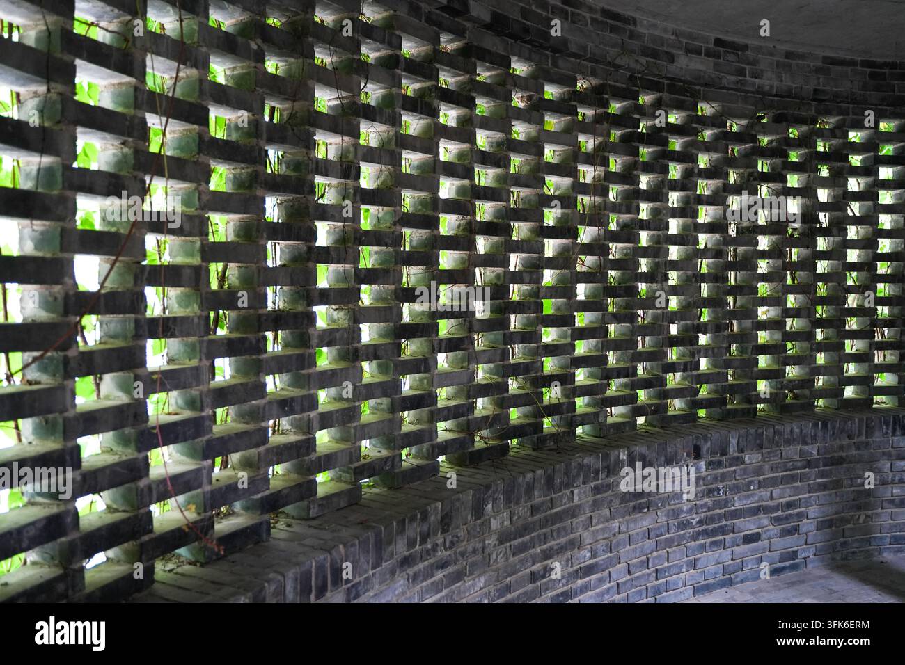 Graue Ziegelgitterwand mit regelmäßig angeordneten quadratischen Fenstern Stockfoto