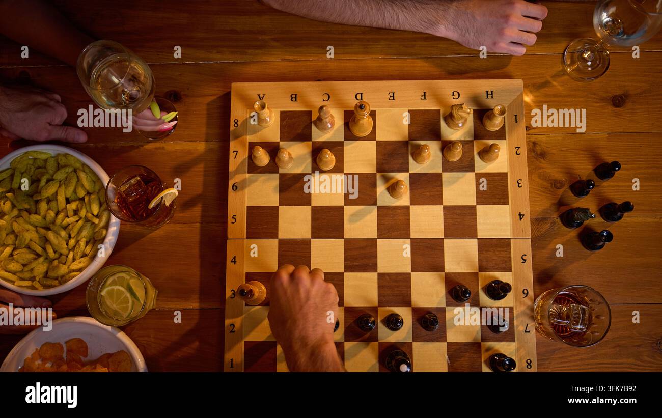 Ansicht von oben: Hände, die während eines strategischen Brettspiels Schachfiguren bewegen Stockfoto